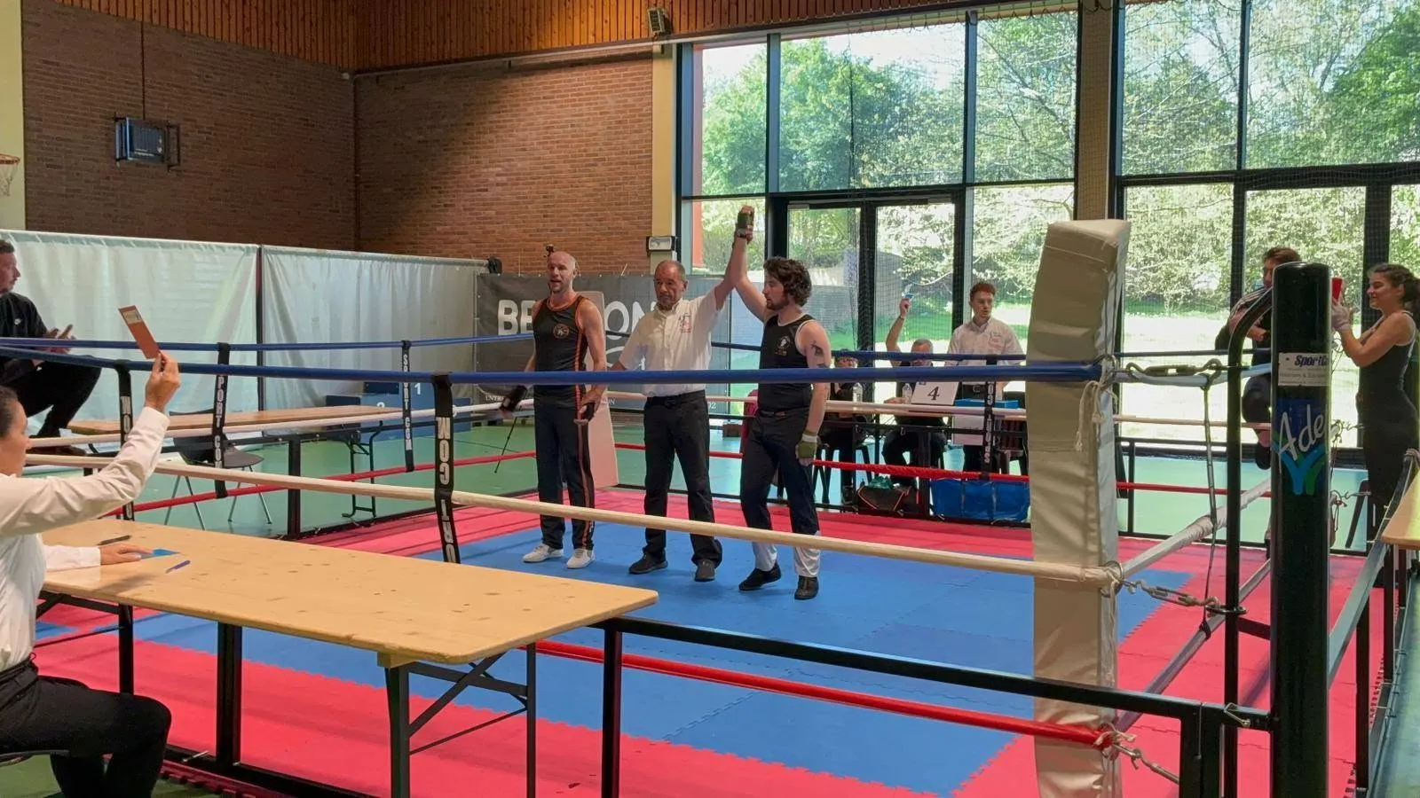 L'arbitre lève le bras de deux compétiteurs vainqueurs