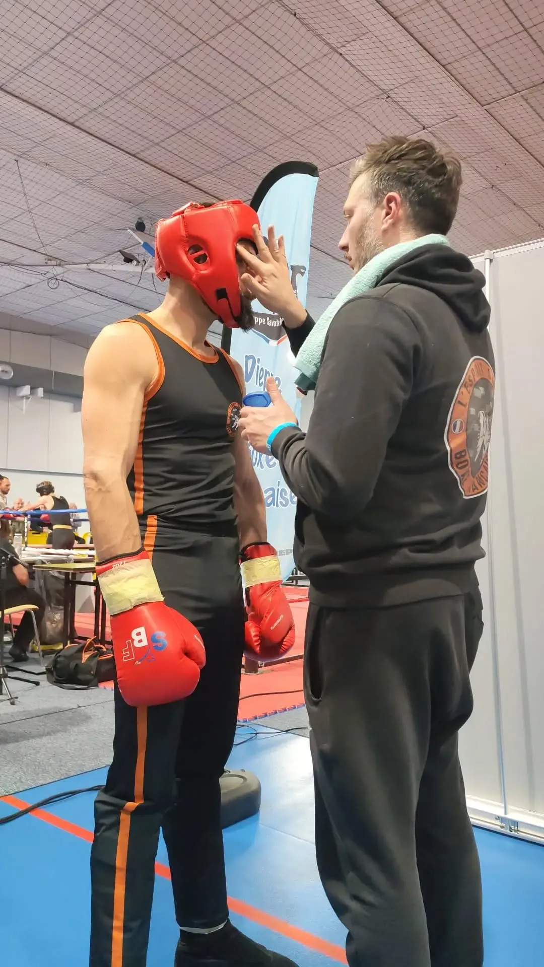 Le coach ajuste le casque d'un compétiteur avant l'assaut